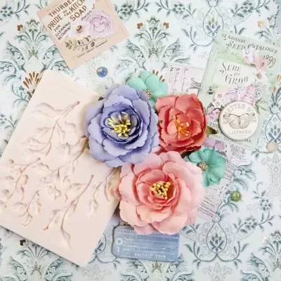 Produtos de cosmética e decoração com flores artificiais, sabão com relevo e embalagens com rótulos, sobre fundo floral