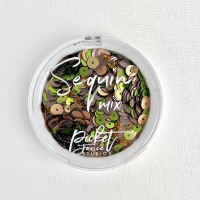 Embalagem redonda de plástico com lantejoulas coloridas e texto branco sobre a tampa