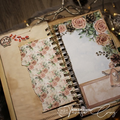 Caderno floral com espiral dourada e decoração de anjo sobre madeira.