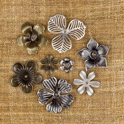 Moedas decorativas em forma de flores de metal prateado e dourado sobre tecido rústico bege.