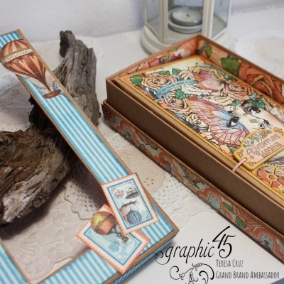 Moldura azul decorada com ilustrações vintage e caixa decorativa colorida numa mesa rendada