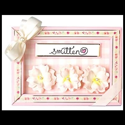 Conjunto de três presilhas florais em caixa rosa com laço e etiqueta smitten