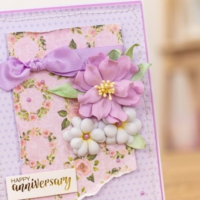 Cartão aniversariante lilás com flores artificiais e fita roxa