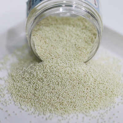 Frasco de vidro com pequenas bolinhas brancas derramando