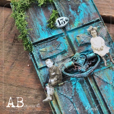 Porta miniatura azul envelhecida com musgo e figuras de crianças com asas em papel