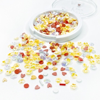 Peças de plástico coloridas em forma de corações espalhadas e recipiente aberto