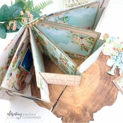 Álbum decorativo floral em tons pastel sobre tábua de madeira com flores ao fundo