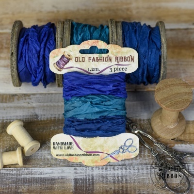 Rolos de fitas de tecido azuis com etiquetas 'OLD FASHION RIBBON' e carretéis de madeira