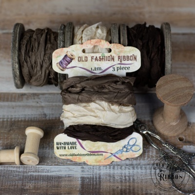 Fitas Old Fashion Ribbon em tons castanhos sobre mesa de madeira com carretéis e tesoura