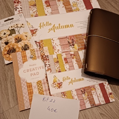 Papeis decorativos temáticos 'Hello Autumn' e autocolantes de flores sobre chão de madeira com caderno castanho