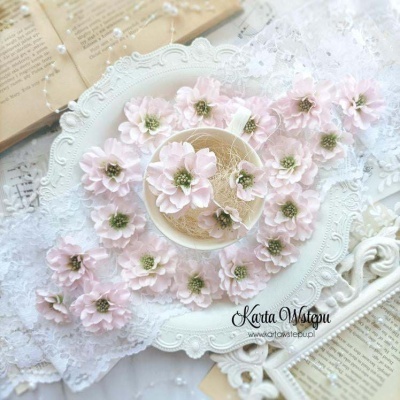 Chávena branca com flores rosa claras em prato branco decorativo sobre toalha rendada e papel