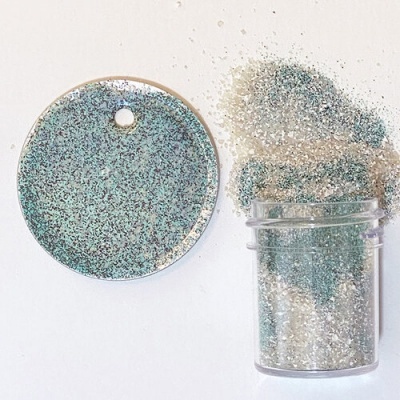 Pó de glitter azul e prateado em frasco transparente e disco redondo com glitter