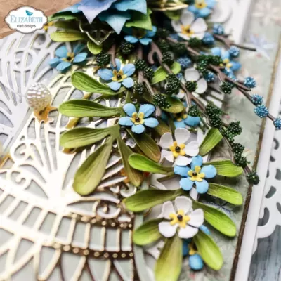 Arranjo decorativo floral azul, branco e verde com padrão recortado e logo ELIZABETH craft designs