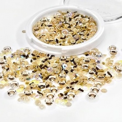 Lantejoulas douradas brilhantes em caixa plástica transparente sobre fundo branco