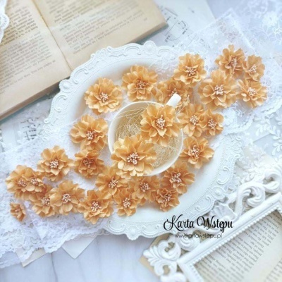 Flores artificiais bege sobre prato branco com fundo de renda e papel