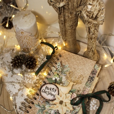 Caderno natalício espiral decorado com estatuetas e vela em ambiente iluminado com luzes de natal