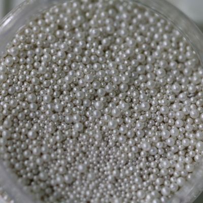 Pérolas brancas artificiais de vários tamanhos num recipiente transparente