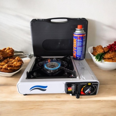 Fogão portátil a gás com queimador aceso e recipiente de gás ao lado