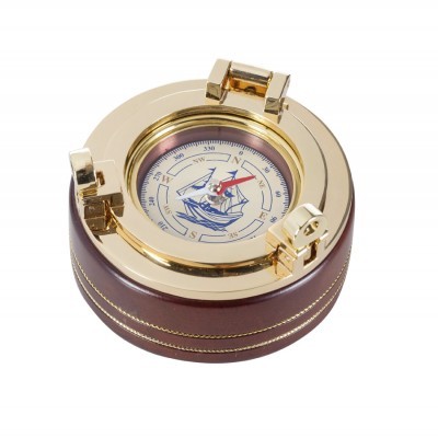 Bússola redonda dourada com base castanha e desenho de navio