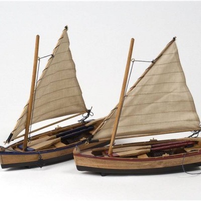 Dois modelos de barco em madeira com velas bege e mastros