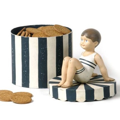 Caixa de biscoitos preta e branca com figura decorativa de menino sentado na tampa.