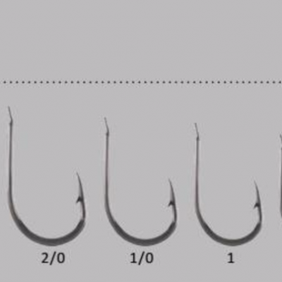 Conjunto de anzóis de pesca metálicos em vários tamanhos, etiquetados e organizados em fila sobre fundo branco.