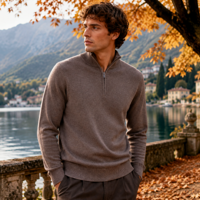Homem com camisola castanha de malha junto a lago e árvores de outono