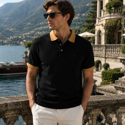 Man wearing black polo shirt with yellow collar by a lake and mountains