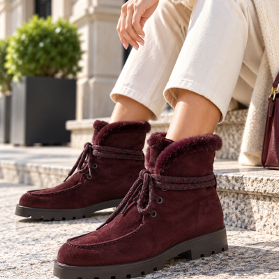 Botas de inverno em camurça bordeaux com forro peludo e atacadores amarrados.
