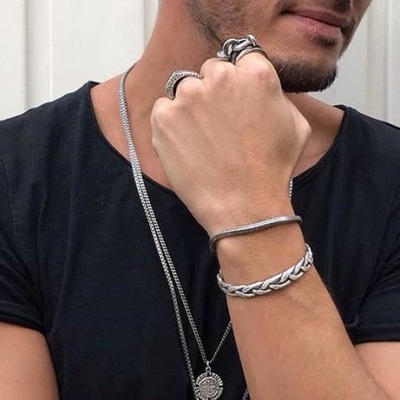 Homem com acessórios de prata usando t-shirt preta.