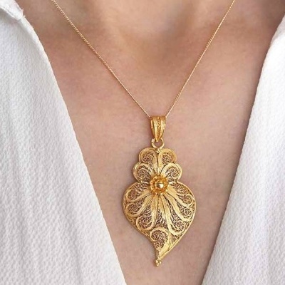 Colar dourado com pendente em forma de folha e flor central no pescoço