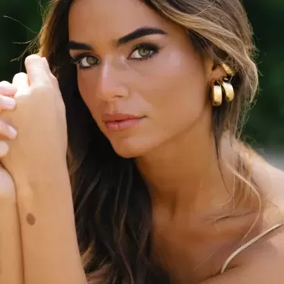 Mulher jovem com brincos dourados e cabelo castanho claro