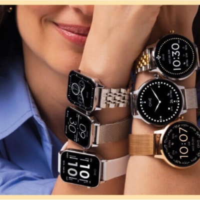 Mulher a usar seis relógios inteligentes variados nos braços.