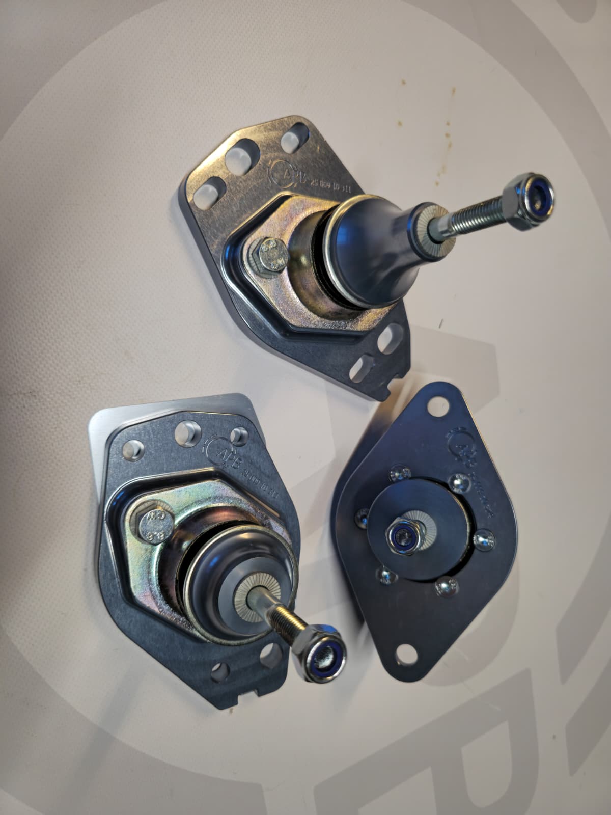 Three metal automotive suspension ball joints with nuts and mounting plates