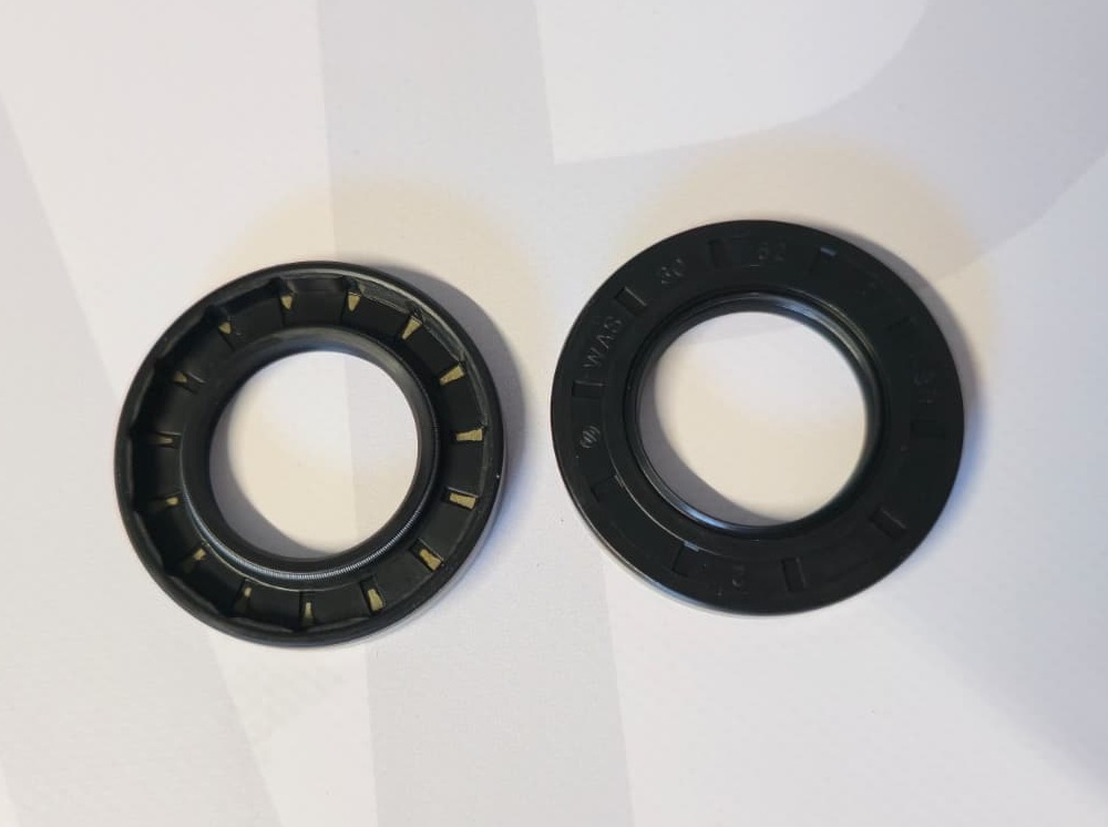 Two black rubber oil seals with embossed text on white surface