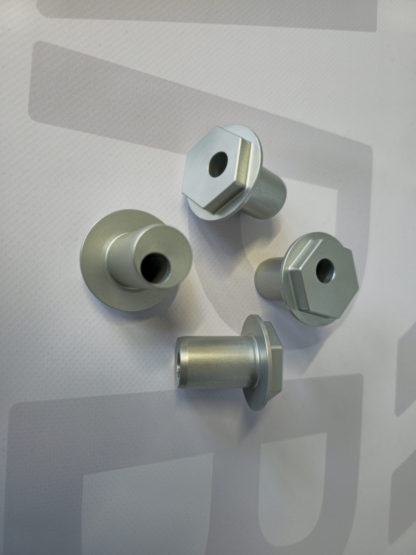 Peças metálicas cilíndricas prateadas com base hexagonal e orifício central