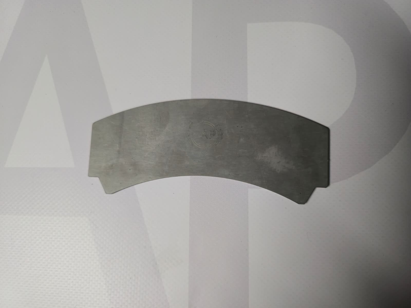 Curved metallic plate with APB logo on white background