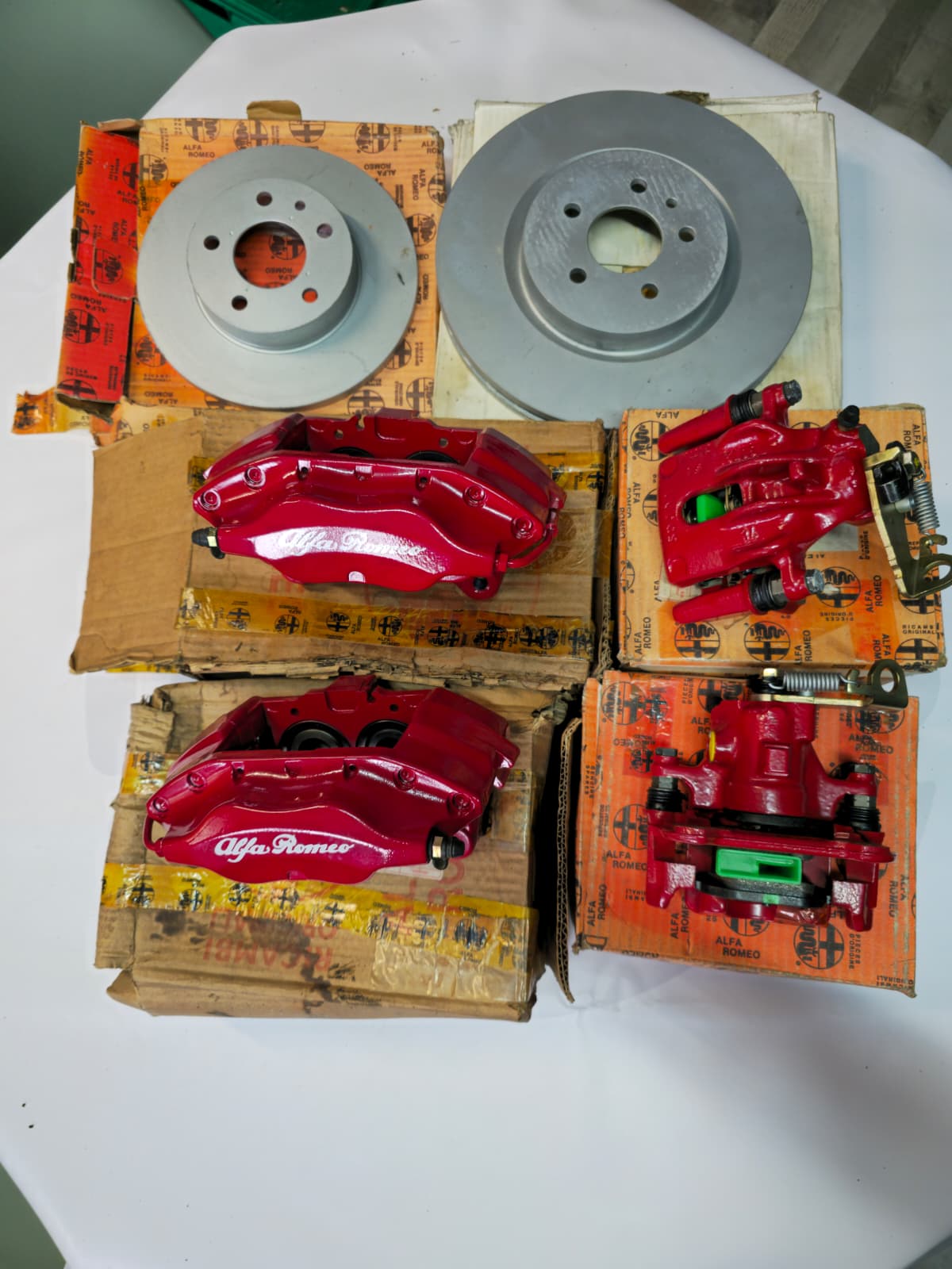 Red Alfa Romeo brake calipers and silver brake discs on branded boxes