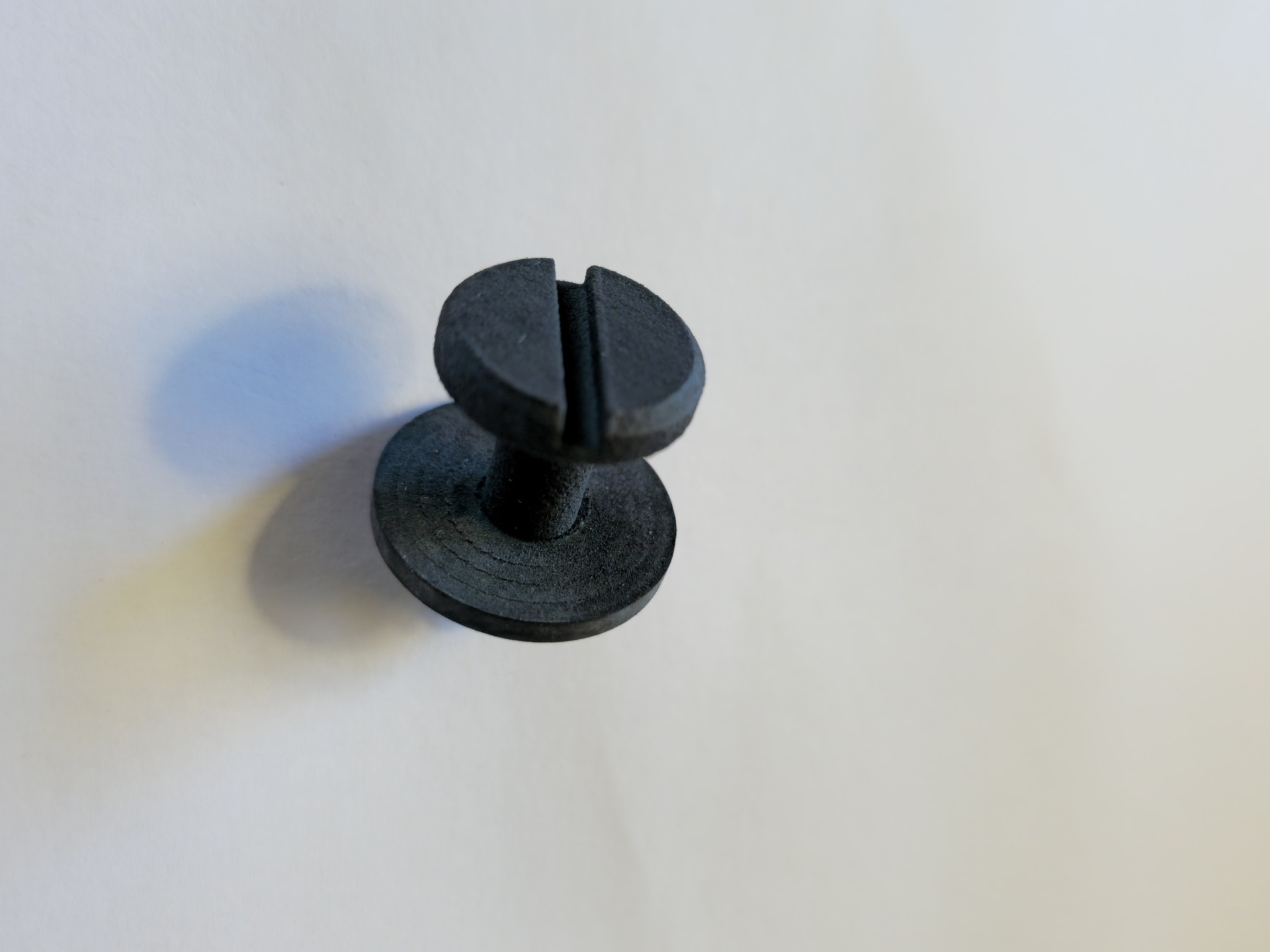 Parafuso preto de cabeça plana com fenda sobre fundo branco