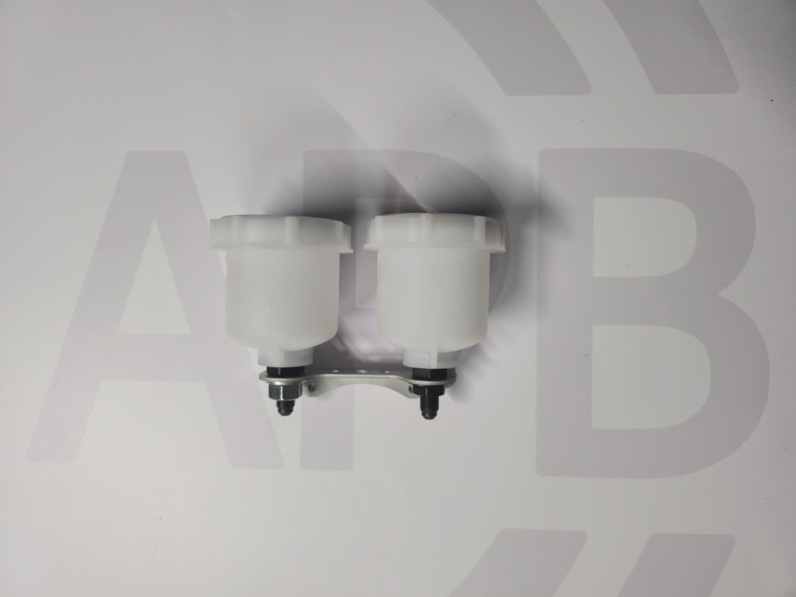 Two white plastic fluid reservoirs with black caps on white surface