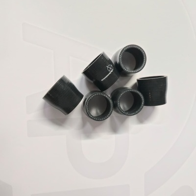 Black rubber cylindrical hose connectors on a white surface