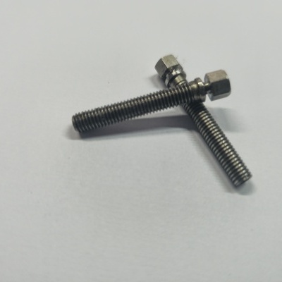 Dois parafusos metálicos prateados com cabeça sextavada sobre superfície branca