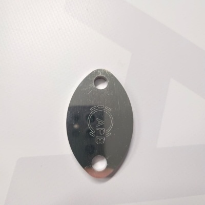 Oval metallic keychain with 'APE' engraving on a white surface