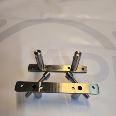 Two metallic mounting brackets with cylindrical pegs on white surface