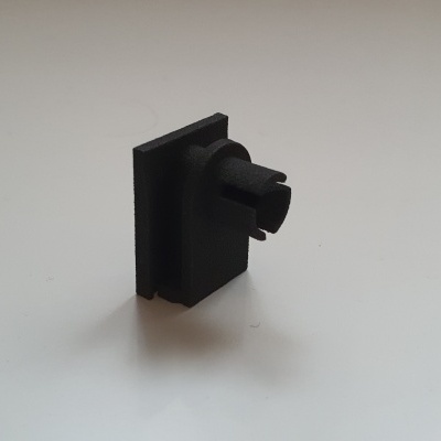 Peça pequena preta com botão em fundo branco