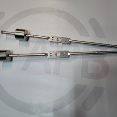 Two metal tools with cylindrical weights and flat sections with holes on a white surface.