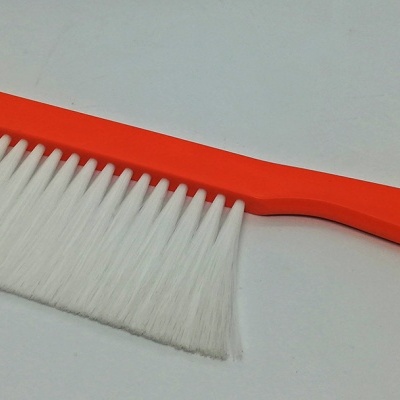 Pente de limpeza com cabo laranja e cerdas brancas