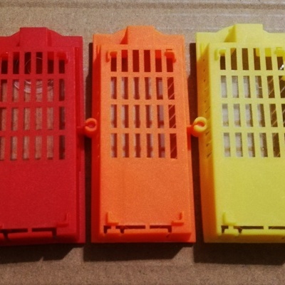 Cinco caixas plásticas coloridas alinhadas, com grelhas e textura lisa, em fundo de cartão