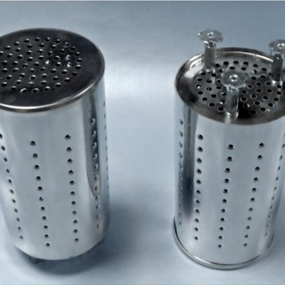Dois filtros metálicos cilíndricos prateados perfurados sobre superfície branca