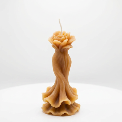 Vela decorativa em forma de rosa castanho claro sobre superfície branca